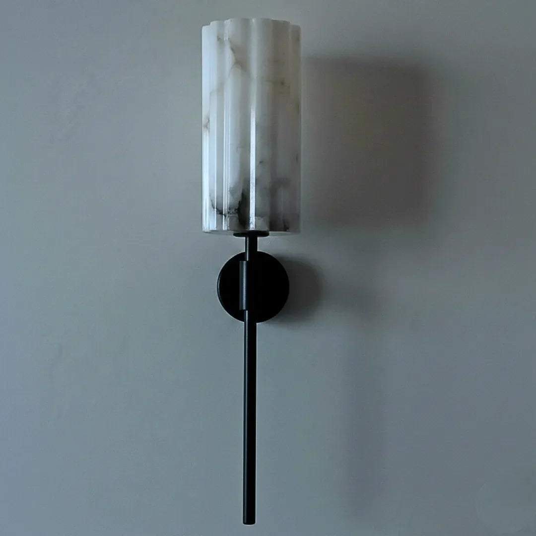 Wall sconce with alabaster marble-like shade and black base on a plain wall