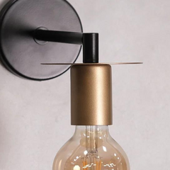 closer look of Modern Industrial Wall Light features a sleek black arm extending from a round base, complemented by a golden socket.