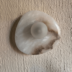 Cream-toned Aureole alabaster wall light mounted on a plain wall, full front view
