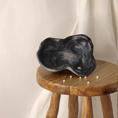Black kai ceramic organic bowls with a swirled edge design, displayed on a white textured surface.