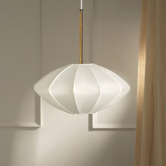A modern pendant lamp with a white and gold geometric design shade, suspended by a brass-like rod, against a neutral background.