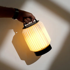 Portable Tote Table Lamp, hand holding a glowing lantern against a neutral background