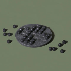Black textured round object with smaller black spheres on a green background