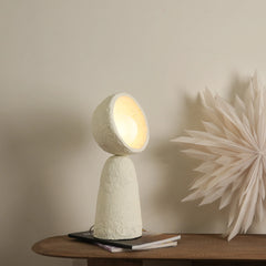 Unique small handcrafted Echo Sphere Table Lamp made from paper mache, with a textured, beige surface and a round top, casting a warm glow.