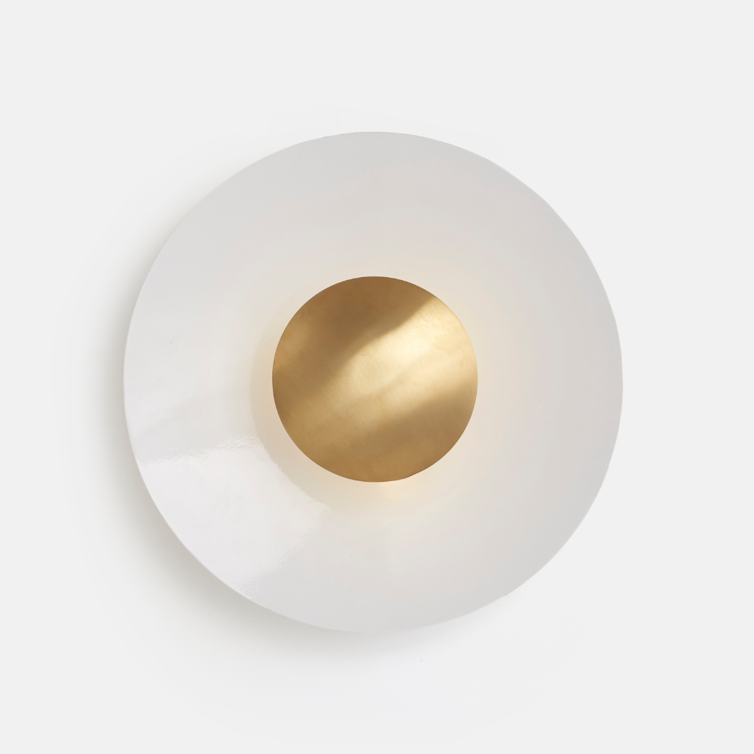 A Disc Wall Light with a white exterior and gold-colored interior light diffuser, mounted on a wall.