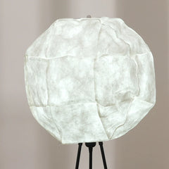 Close view of unique floor lamp with a tripod base and a spherical lampshade with a white shade.