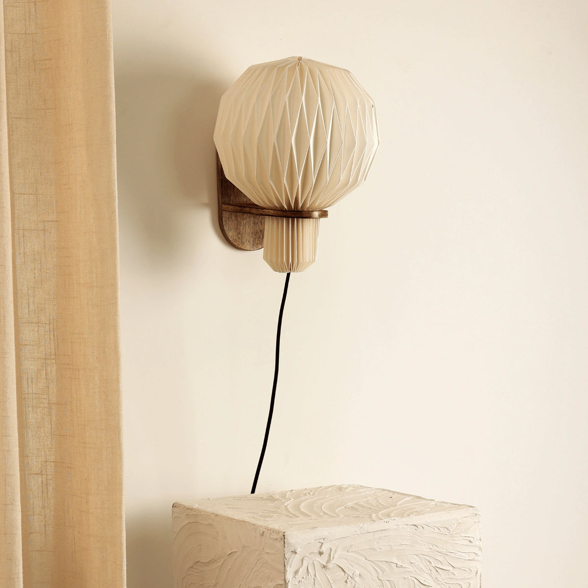Aura Pleat wall sconce casting ambient glow in interior