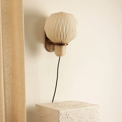 Aura Pleat wall sconce casting ambient glow in interior