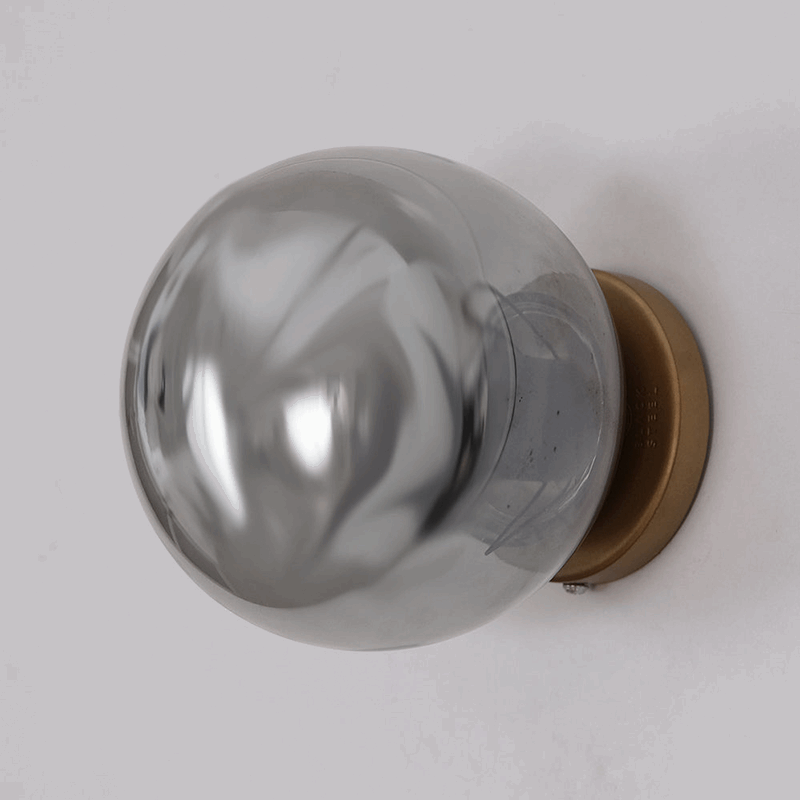 Close up of black steel Aurora Noir Wall Sconce with gold wall rose