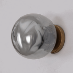 Close up of black steel Aurora Noir Wall Sconce with gold wall rose