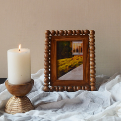 Close look of Globule wood photo frame placed next to a candle holder with wooden base