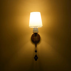 Stripe Wall Light with white fabric shade, ceramic stem having graphic black-and-white striping and brass arm casting warm ambient glow