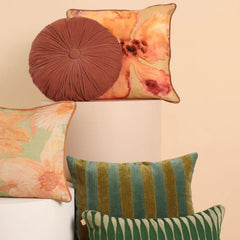 A styled collection of decorative throw Holly Eucalyptus Velvet Stripe Cushion Cover displayed on white pedestals against a warm beige wall. 