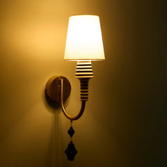 Stripe Wall lamp with white fabric shade, ceramic stem and a warm brass arm giving warm, ambient glow