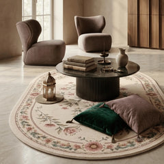 Modern living room with round coffee table, chairs, and decorative pillows on a floral rug.
