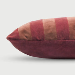 A close-up of a rectangular Holly Spice Velvet Stripe Cushion Cover with vertical stripes in dusty rose, muted red, and tan velvet, with a solid dusty rose base.