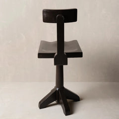 A modern black wooden swivel stool with a curved seat and backrest