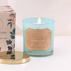 Illume Midi - Lid Jar Candle - Aqua - Orange Cassis - Set of 2, close-up of lit aqua pressed glass with gold label