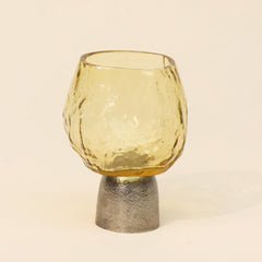 Yellow glass tealight candle holder with textured Sandcast metal base on a beige background