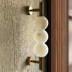Side view of alabaster wall lamp showing stone texture and metal base holding from top and bottom