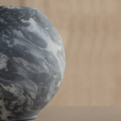 Close view of Marble-patterned Bella Black Vase on a beige background