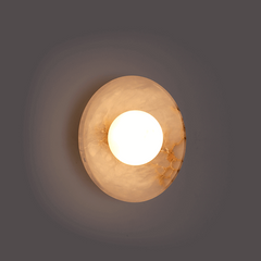 Glowing look of mottled stone and brass hardware of Blot wall sconce