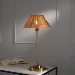 Handcrafted Natural Cane Table Lamp with woven shade and brass metal base and rod on a marble surface against a gray wall.
