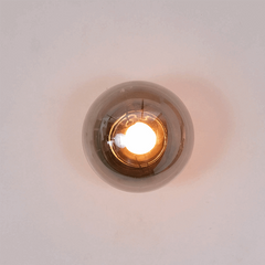 The Aurora Noir sconce uses contrast — dark steel frame with a gold accent