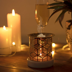 A lit wax warmer with candles and a glass of wine in a cozy setting.