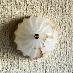 Decorative white Spiral Alabaster Wall Light with a gold center on a textured beige background