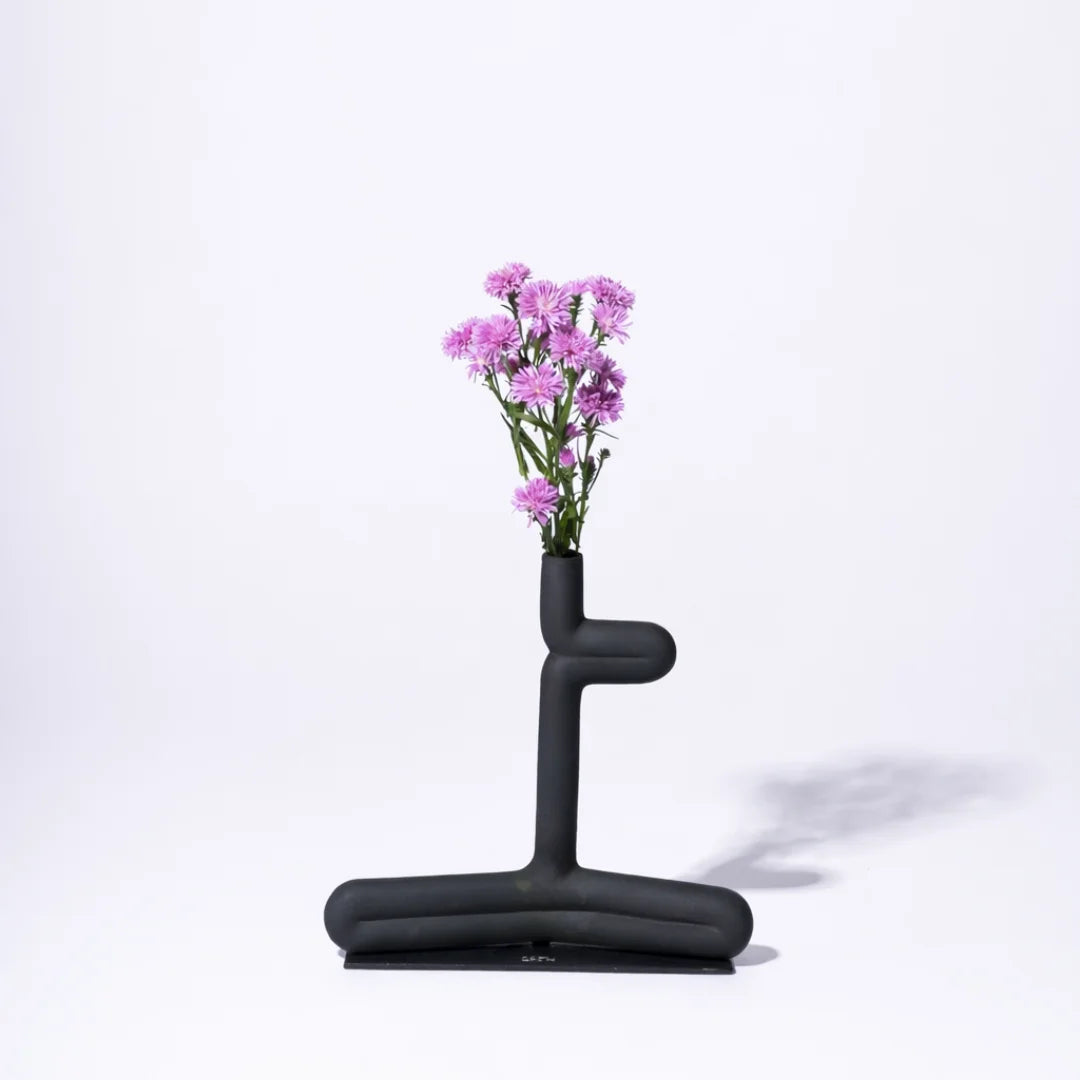 Decorative Black abstract vase with pink flowers on a white background