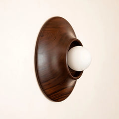 Teakwood wall sconce with a white bulb on a beige background