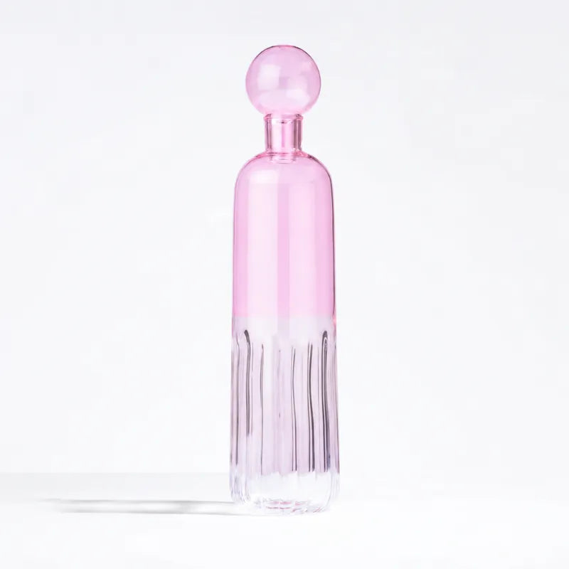 A pink glass water bottle with a matching spherical cap, featuring a flared ribbed base, set against a clean white background.