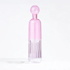 A pink glass water bottle with a matching spherical cap, featuring a flared ribbed base, set against a clean white background.