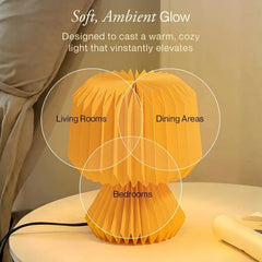 A Orilamp pleated paper-style table lamp glowing with a warm ambient light. White text at the top describes the soft glow, and circles label common use cases: Living Rooms, Dining Areas, and Bedrooms.