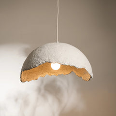 A handcrafted pendant lamp made from recycled paper, with a natural, textured finish and a sleek, minimalist shape, hanging in a dimly lit space.