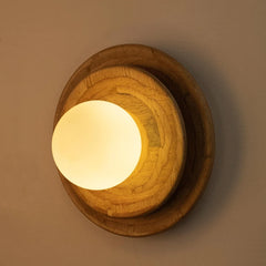 Wooden Tiered wall-mounted light fixture with a warm glow on a beige wall.