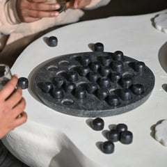 Black stone game board with pieces on a white coffee table