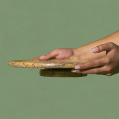 Hand holding a cork coaster on a green background