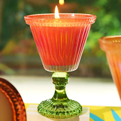 Sundae Votive Candle - Petal · Berry Blonde, lit candle against a garden backdrop, lifestyle view