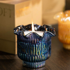 Oud Votive Candle, lit close-up on wooden table showing ribbed iridescent glass texture