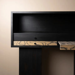 A close-up of a premium dark wood desk or cabinet with a black finish and a drawer featuring a contrasting light beige wood grain front