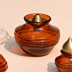 Amber glass container with gold oil lamp cap on a beige background