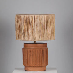 Dune Table lamp with a textured brown terracotta base and raffia beige lampshade on a gray background