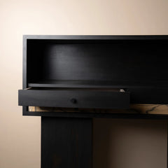 A close-up of a luxury black wooden cabinet or desk with an open shelf and a slightly pulled-out drawer
