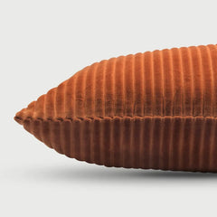 A close-up of a Luna Burnt Orange Velvet Cushion Cover, showing its textured corduroy-like fabric and stitched edges, set against a light gray background.