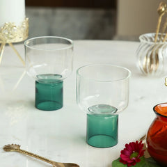 LIFT - Chaat Bowl or Drink Glass in teal – two borosilicate glasses with raised teal bases on a marble table