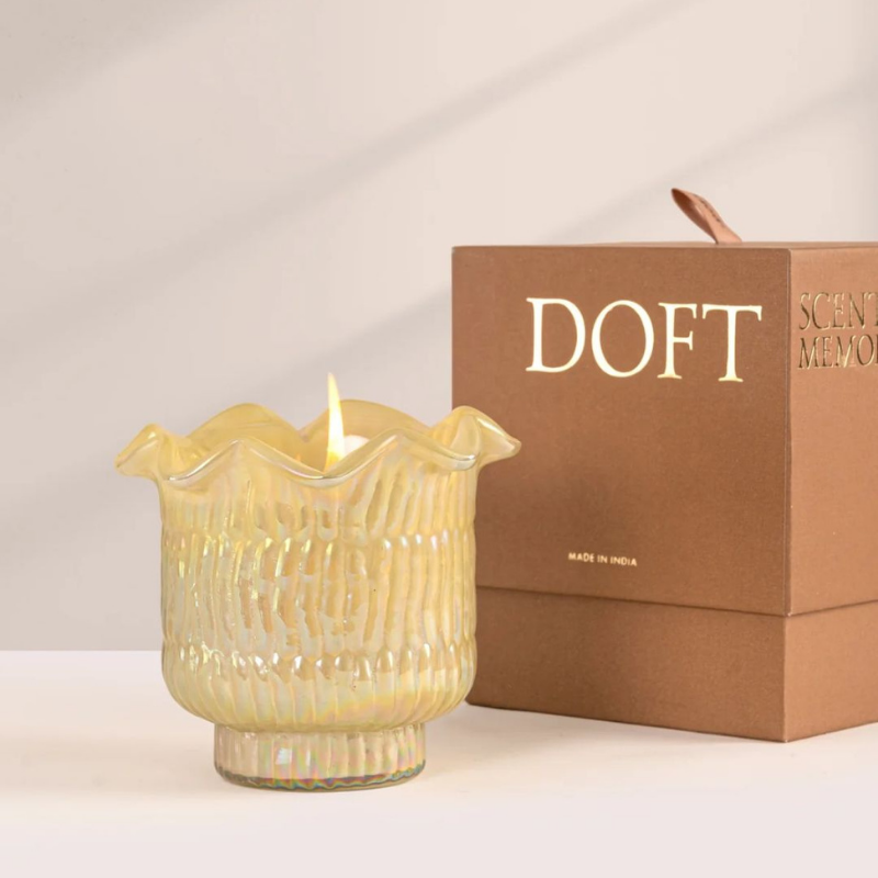 Venetian Bergamot Votive Candle, lit yellow lotus-cut glass votive beside Doft gift box