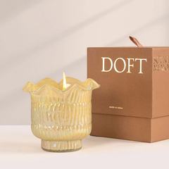Venetian Bergamot Votive Candle, lit yellow lotus-cut glass votive beside Doft gift box
