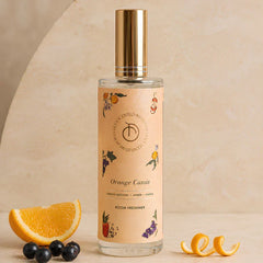 Illume - Room Freshener - 100 ML, Orange Cassis spray bottle with gold cap beside orange and blueberries